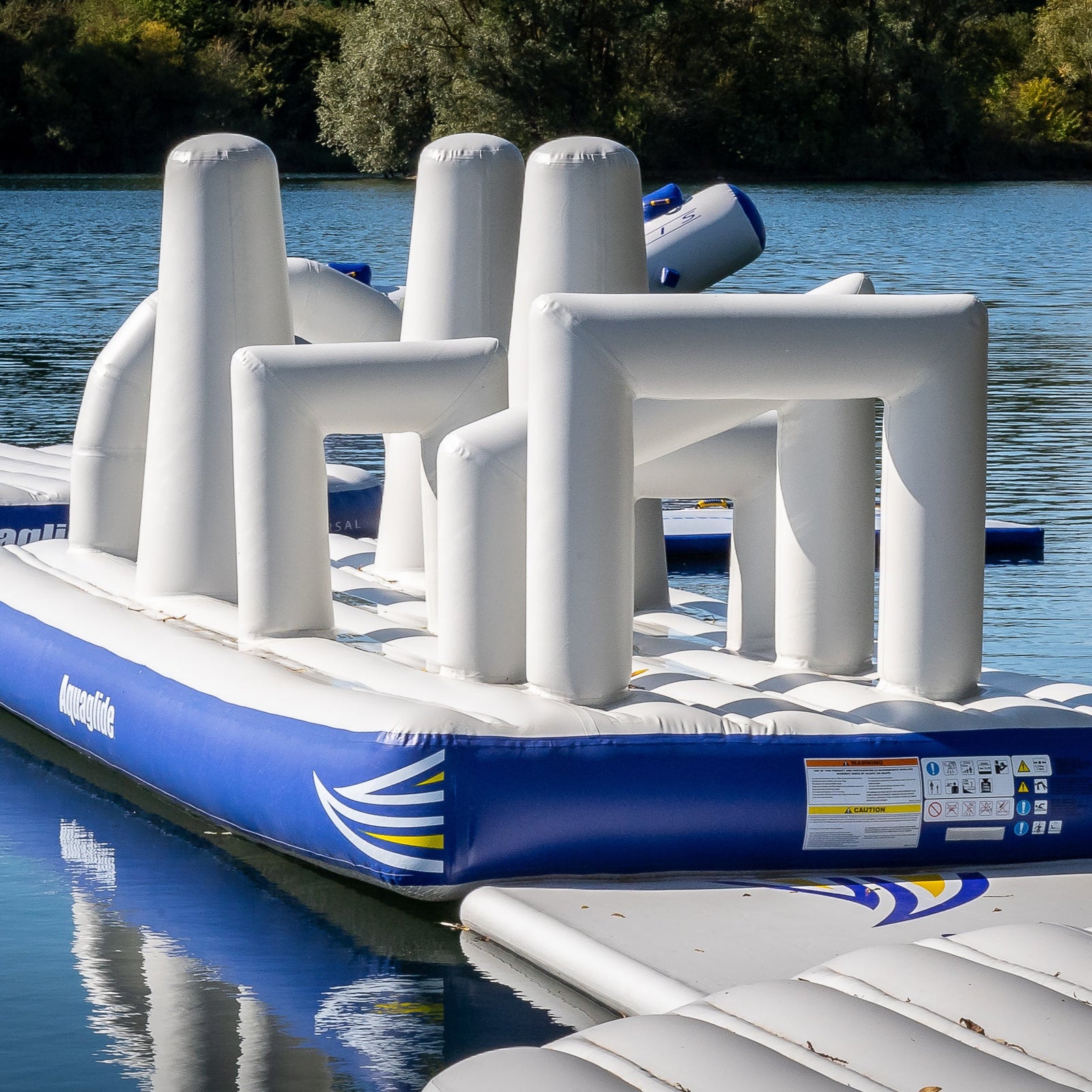 Inflatable water obstacle course with multiple white barriers on a blue platform.