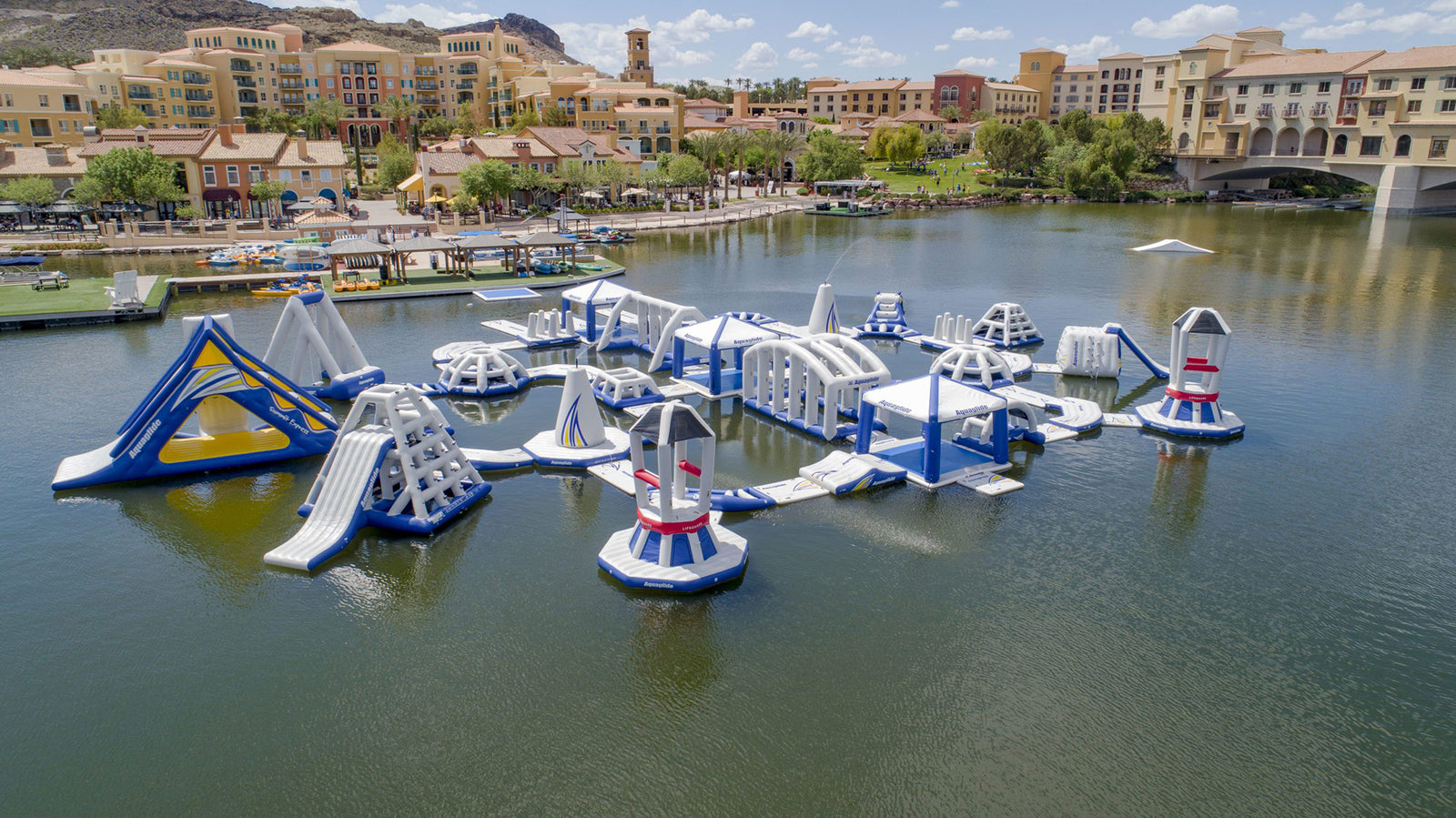 Floating inflatable water park with slides and climbing structures on a lake.