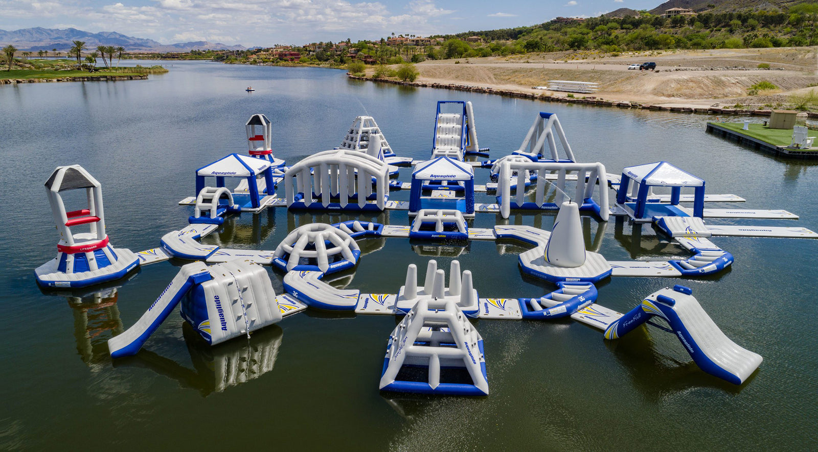 Inflatable water park on a lake with slides and climbing structures.