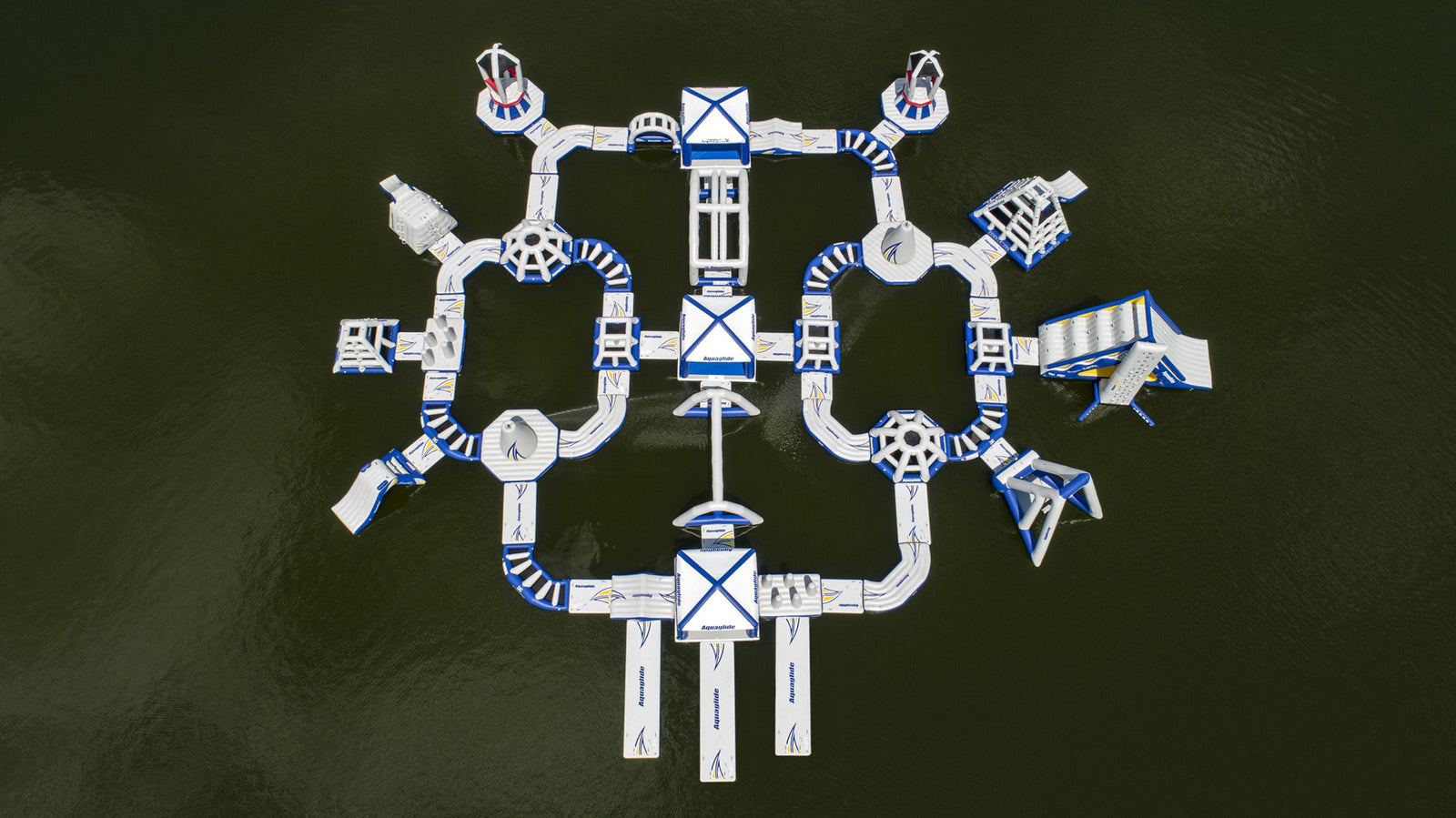 Aerial view of an inflatable water park with slides and paths on a green lake surface.