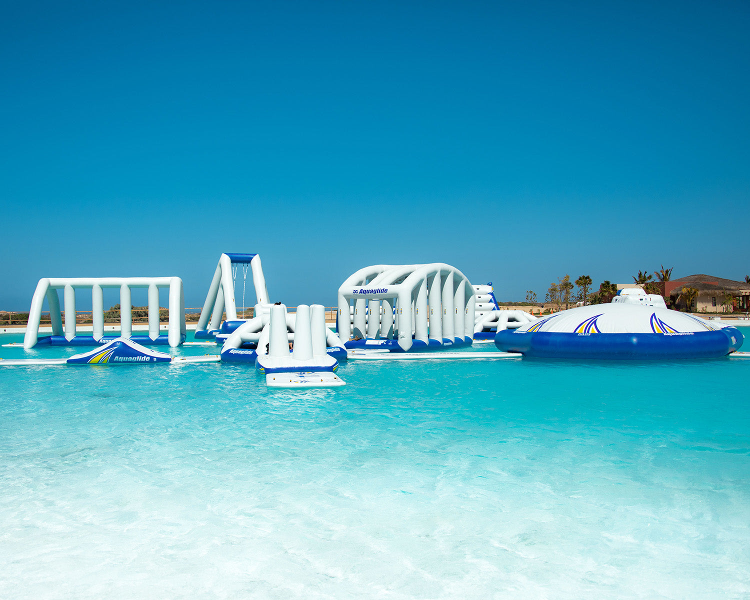 Inflatable water park on clear blue water under a bright blue sky.