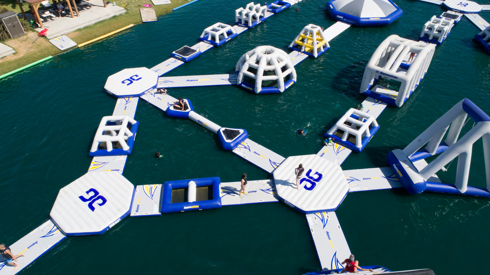 Floating inflatable water park with slides and obstacles on a lake.