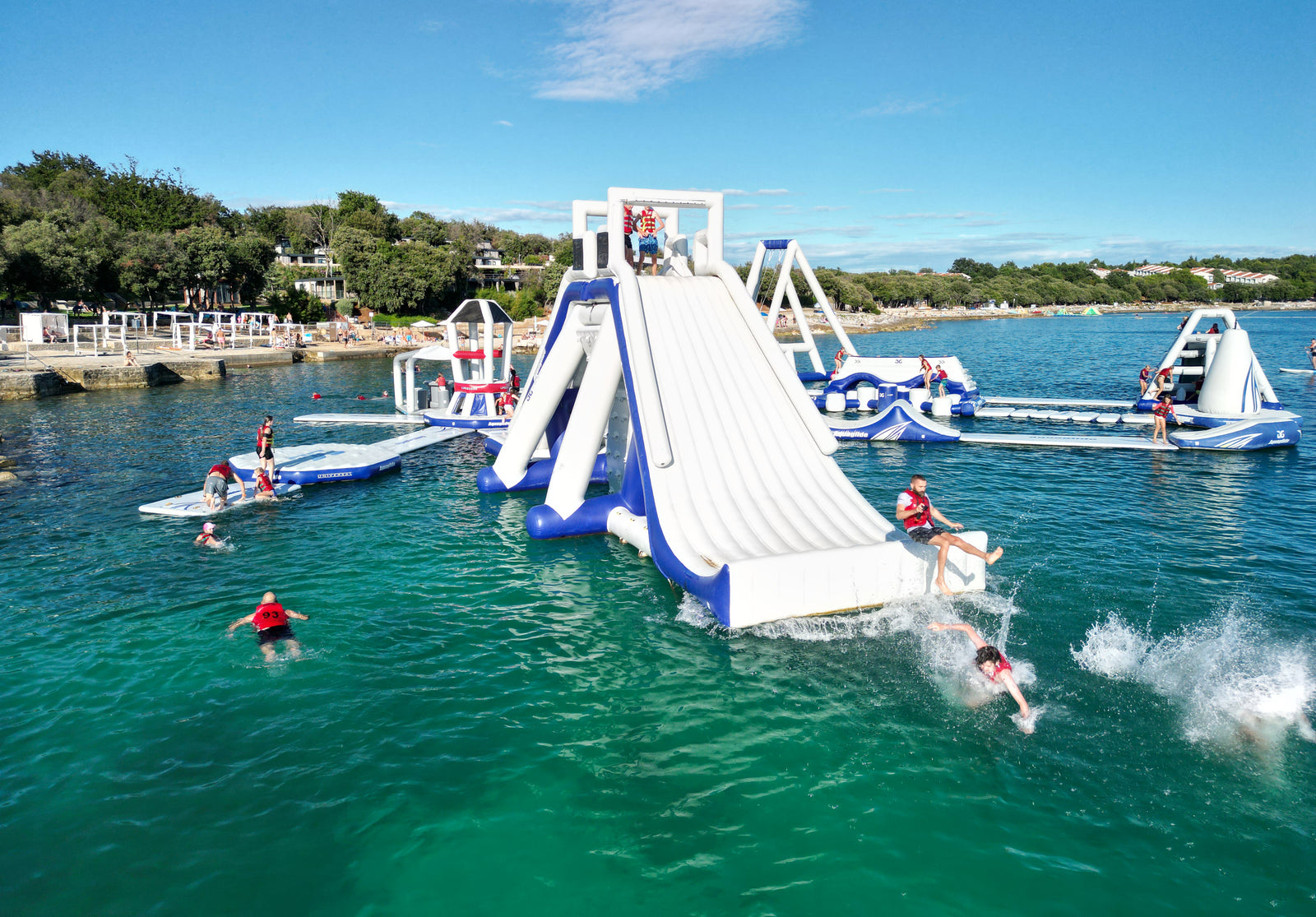 Aquaglide inflatable water slides and platforms in water with people enjoying the activities.
