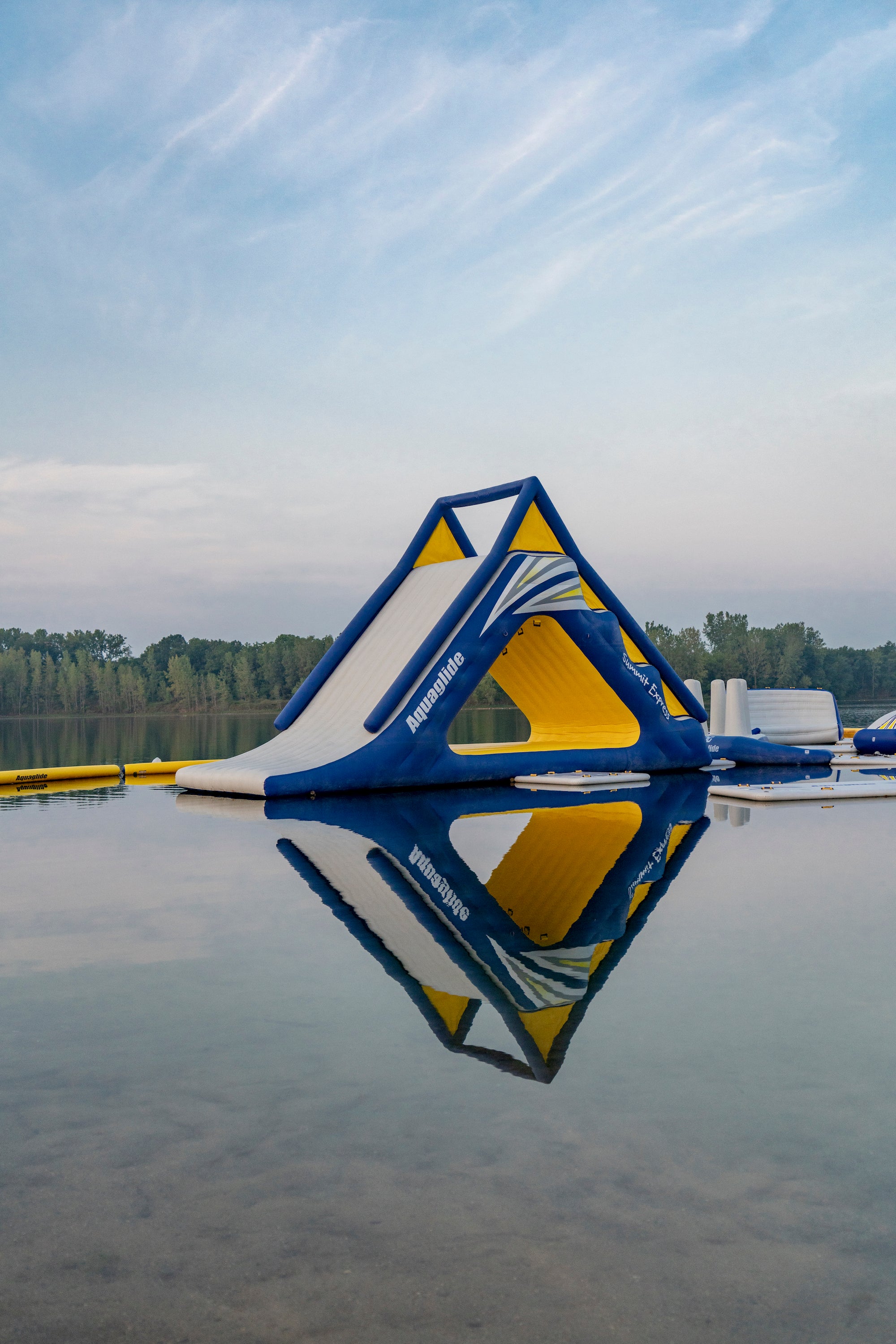Angled view of Aquaglide slide with bold yellow interior floating on glassy lake.