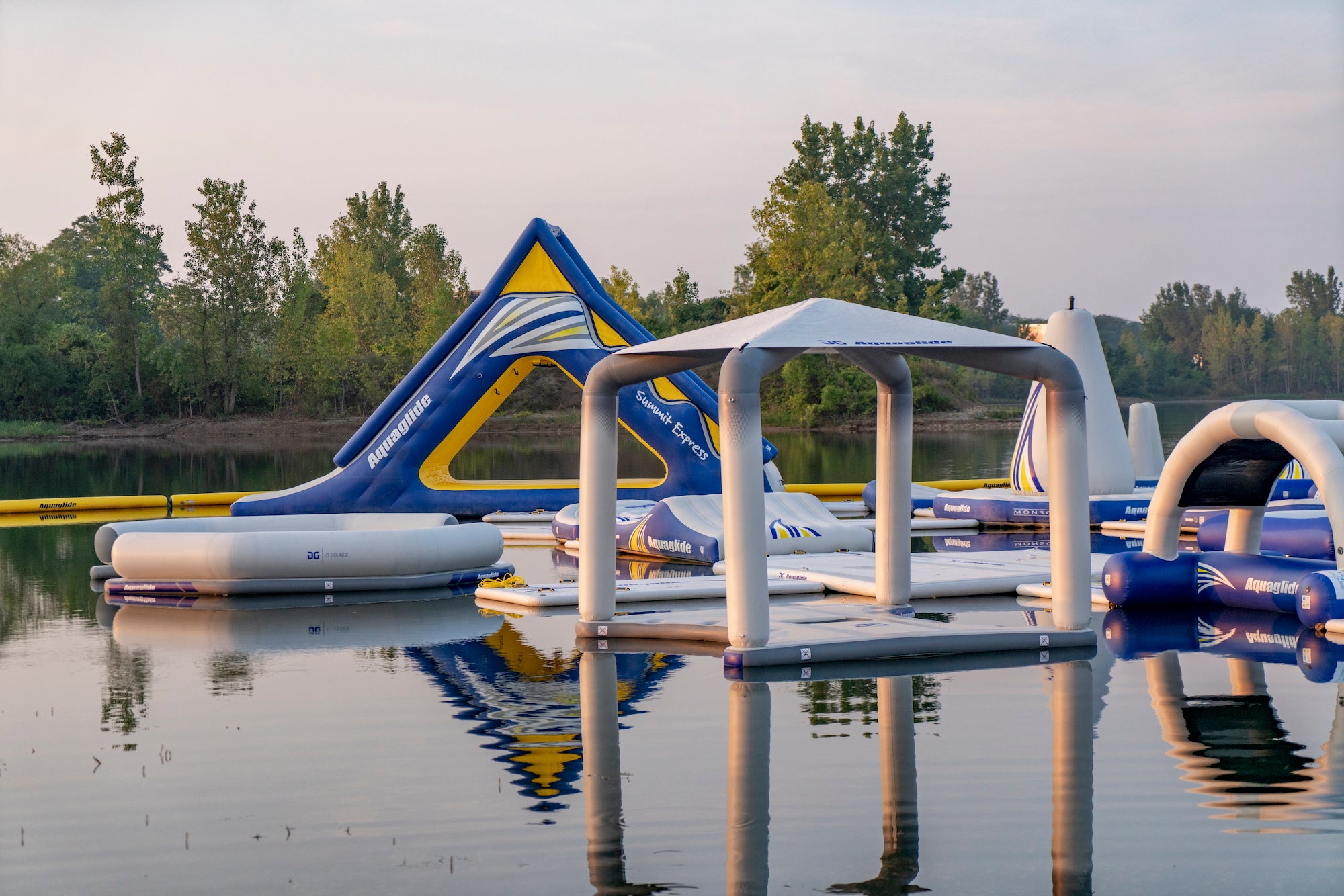 Side view of Aquaglide slide, canopy deck, and lounge float on reflective lake.