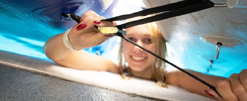 Woman fastening a black strap to the underside of an inflatable structure.