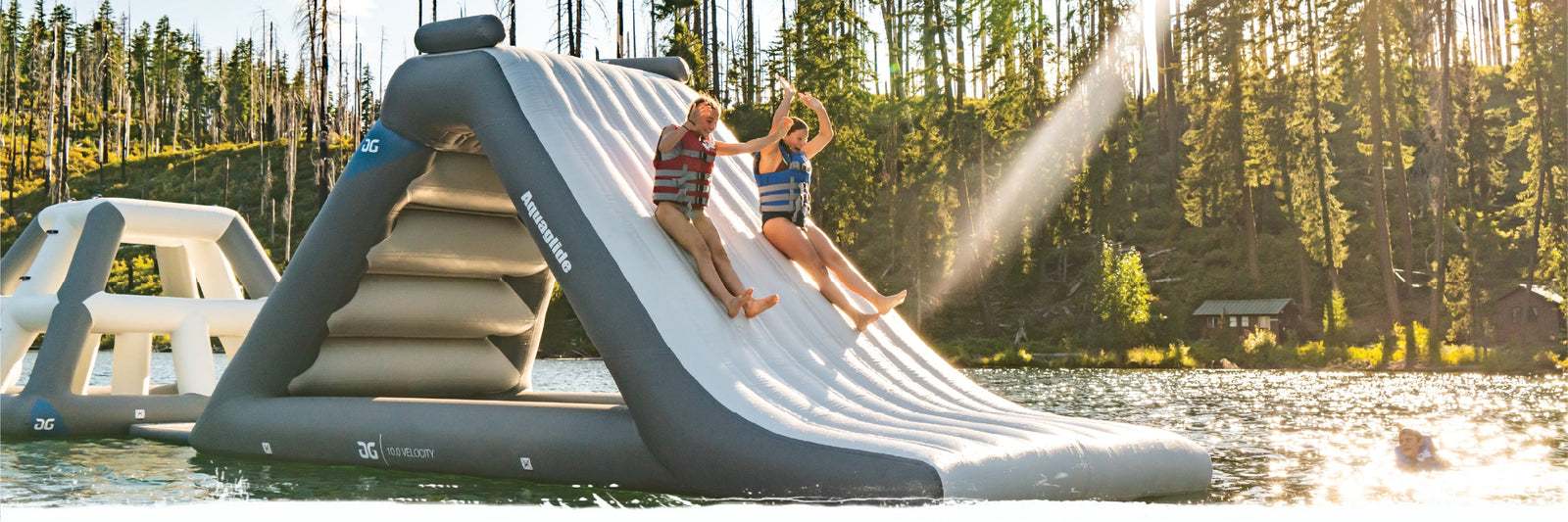 Floating inflatable course on a calm lake surrounded by trees and forested shorelines.