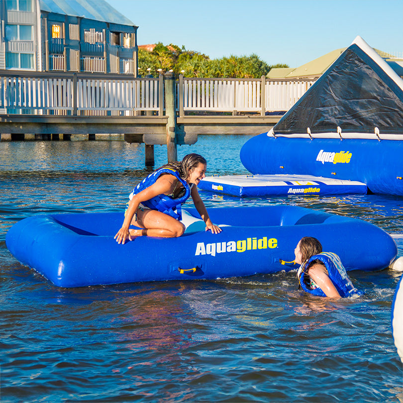 Two people enjoying a Delta 10 inflatable water platform on a lake.