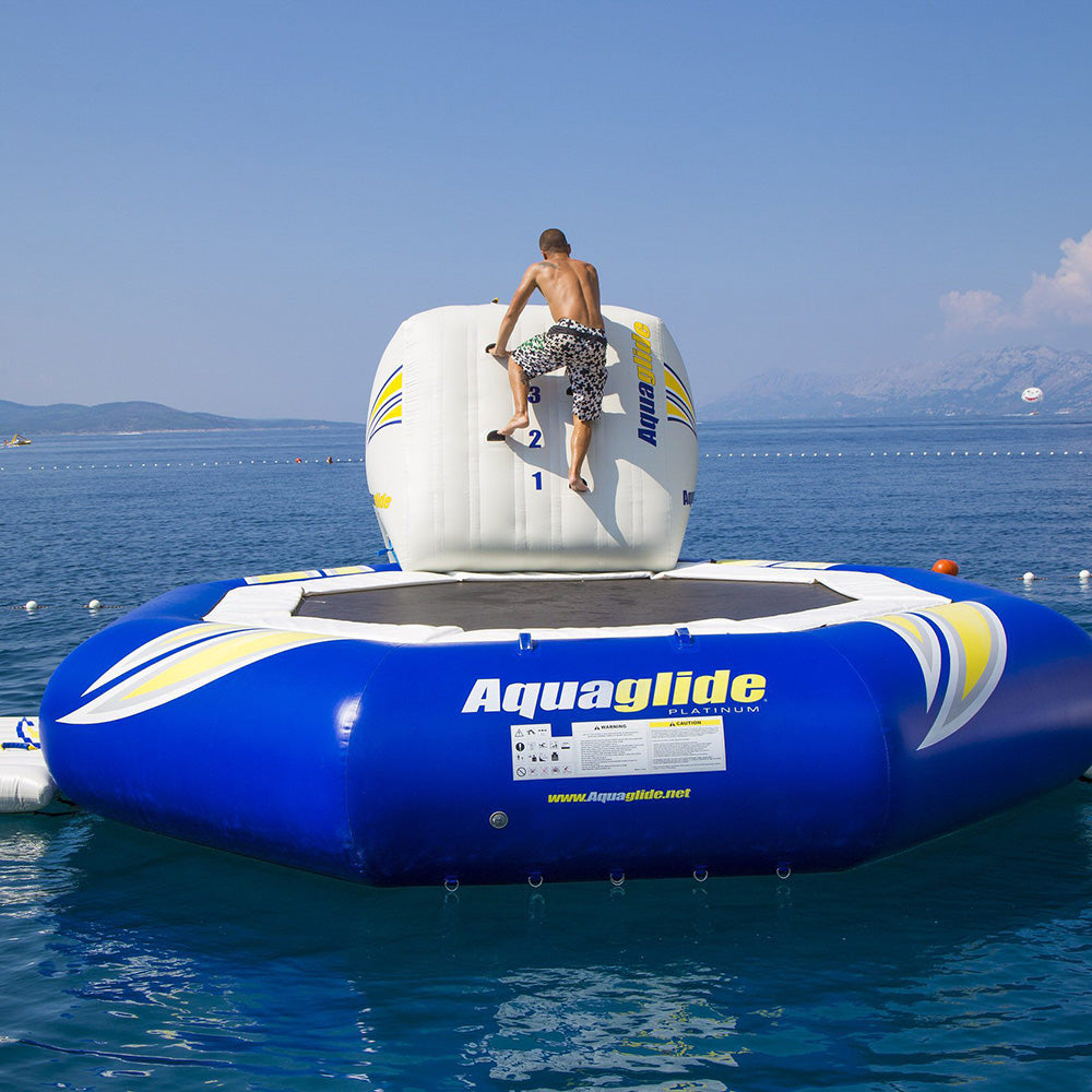 Climber scales an Escalade 3M inflatable on a sunny beach day.