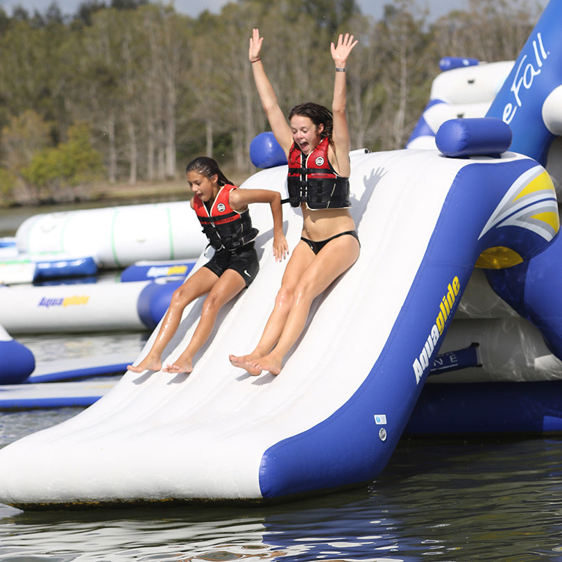 Two people in life jackets enjoy the Freefall 6 inflatable slide.