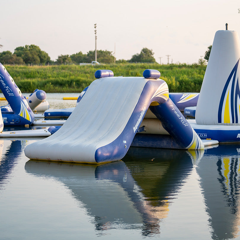 Aquaglide Freefall 6: inflatable water slide and obstacle course on a calm lake.