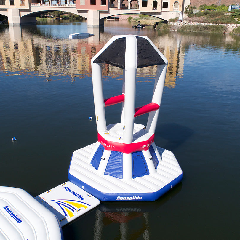 Universal Lifeguard Station floats on calm water near a bridge.