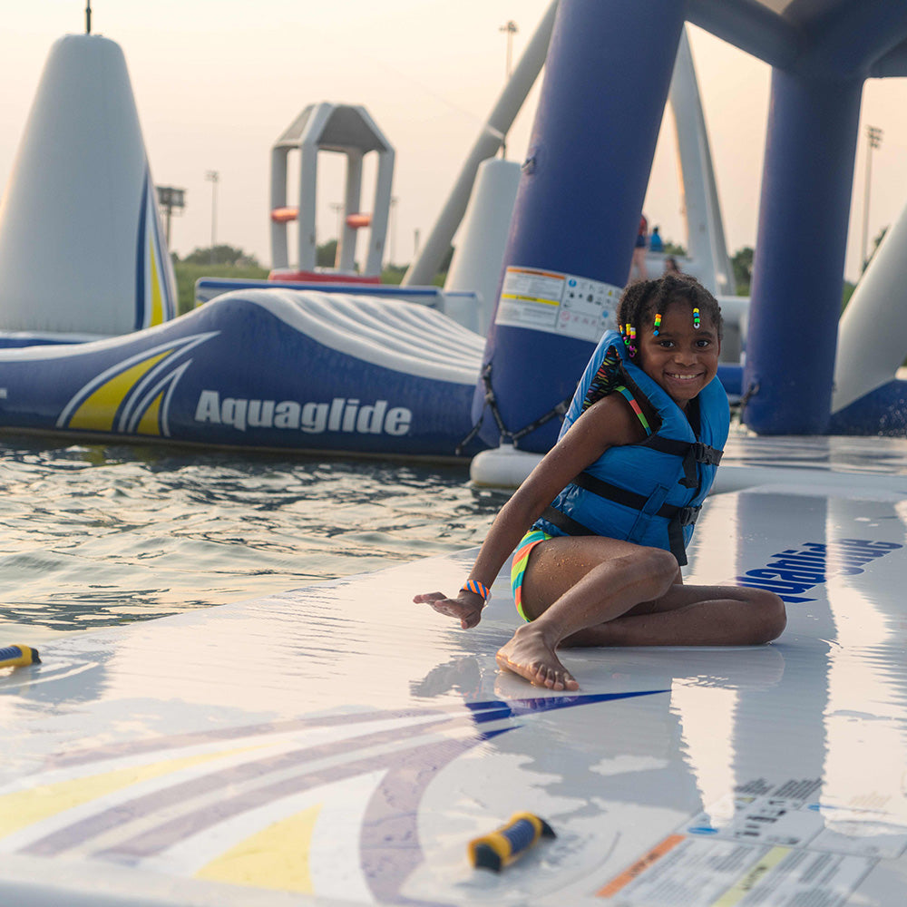 Child in Speedway 10 jacket enjoying floating platform fun at the aquapark.
