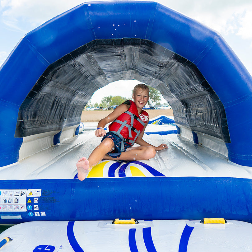 Child in life jacket smiling on the Subway 10 inflatable tunnel.