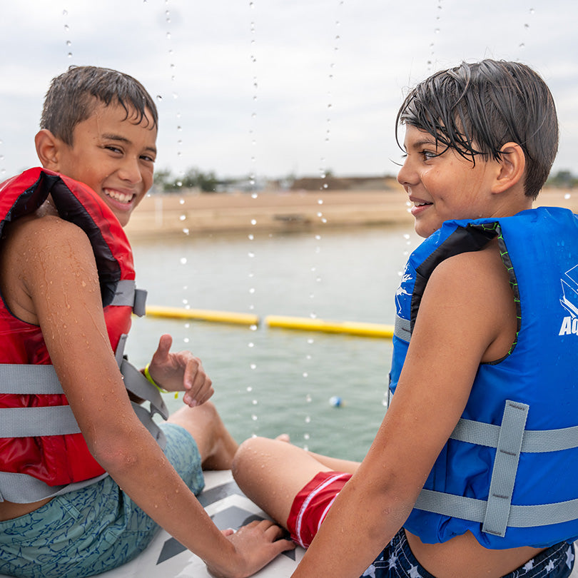 Two kids in life jackets smile while sitting by the Summit Express TR.