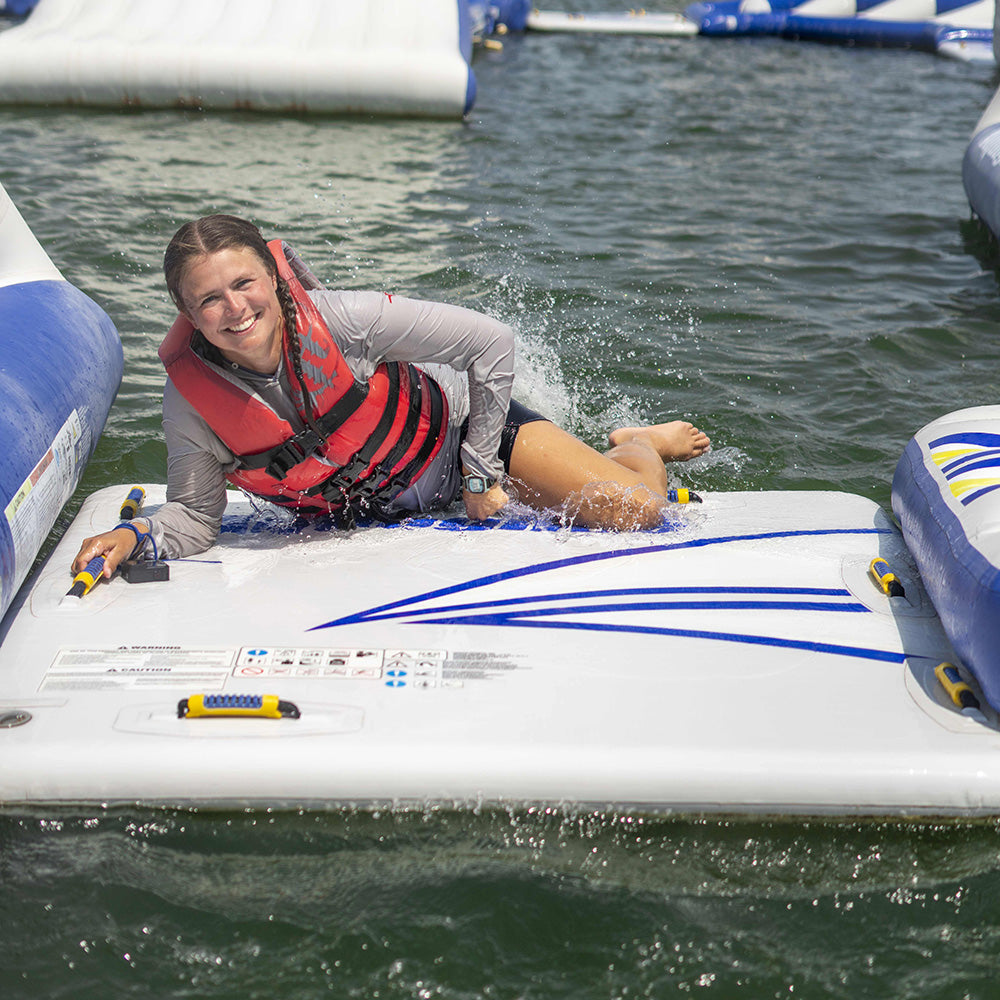 Person smiling on the Swimstep 5x5, wearing a red life jacket in water.