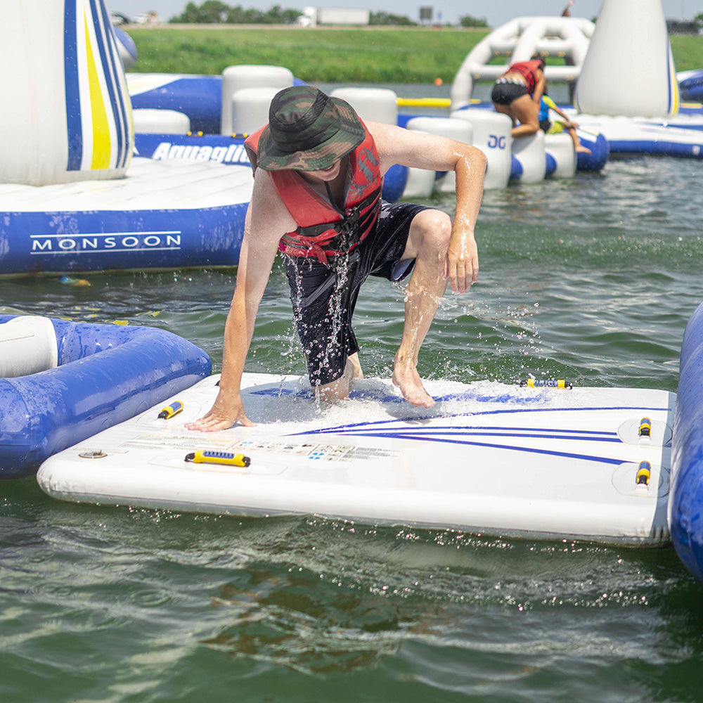 Person kneels on Swimstep 5x5 in red lifejacket, hat, and sunglasses.