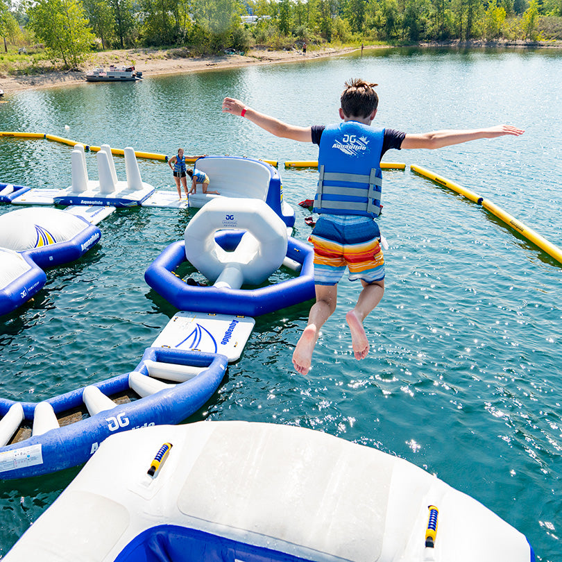Person leaps into lake from Thor, an inflatable course with high-velocity chute slides.