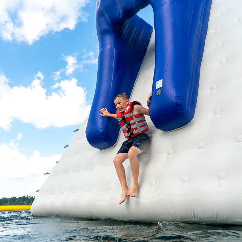 Child sliding down the Thor chute slide in a life jacket on a sunny day.