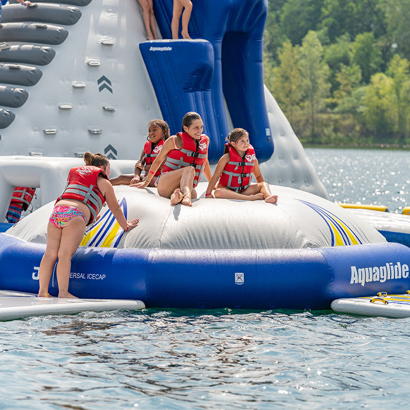 Participants wearing Universal Icecap life vests tackle an inflatable challenge on a sunny day.