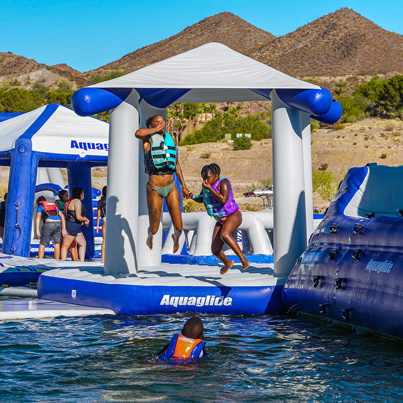 Kids play on the Universal Pavilion inflatables by a lake with hills surrounding them.