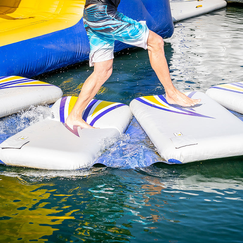 Person leaping on Walkback challenge track pads on water.