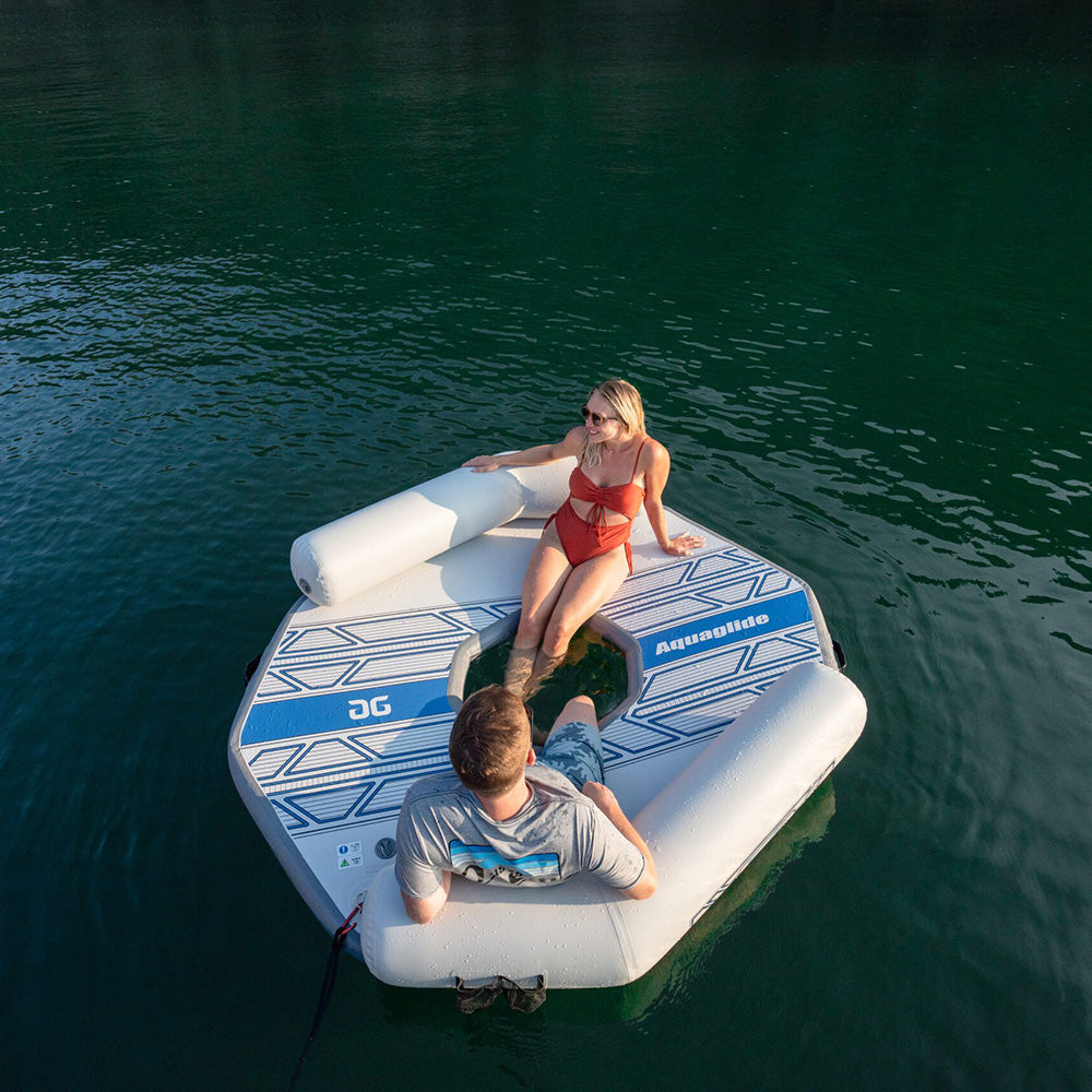 Two people relaxing on a Backside Lounge inflatable with bolster backrests on a lake.