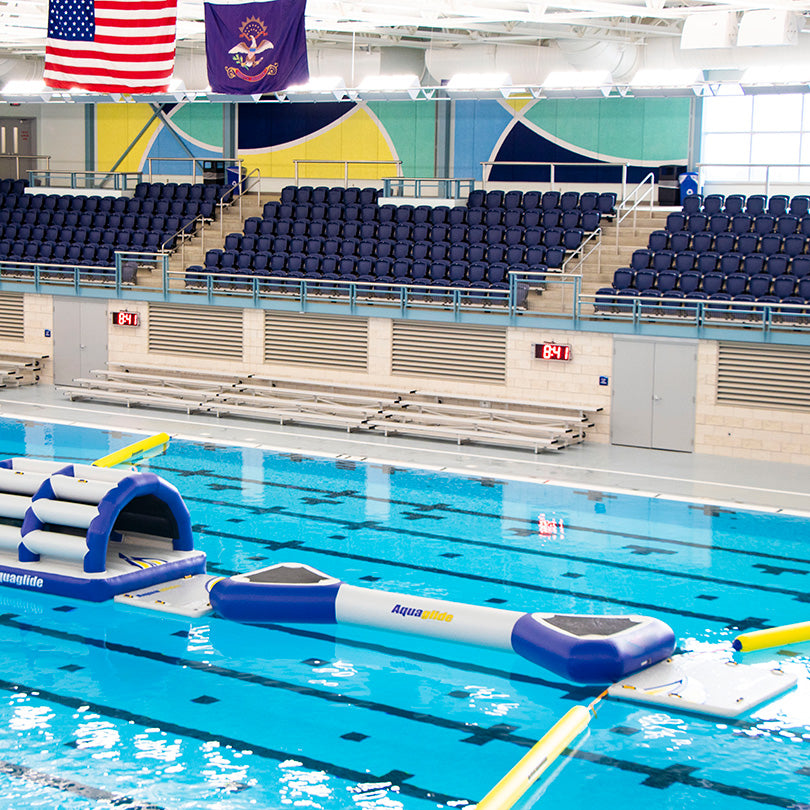 Indoor pool with Challenge Track S inflatable course, limited lane space, flags overhead.