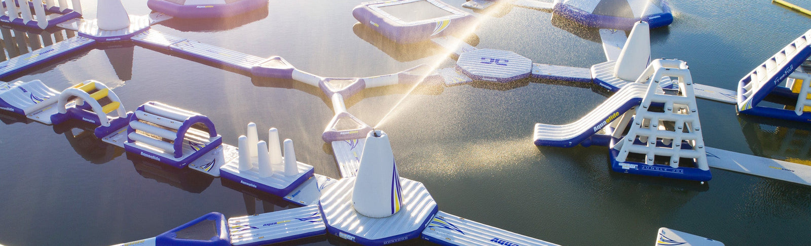 Floating inflatable water park with slides and climbing structures on a sunny day.