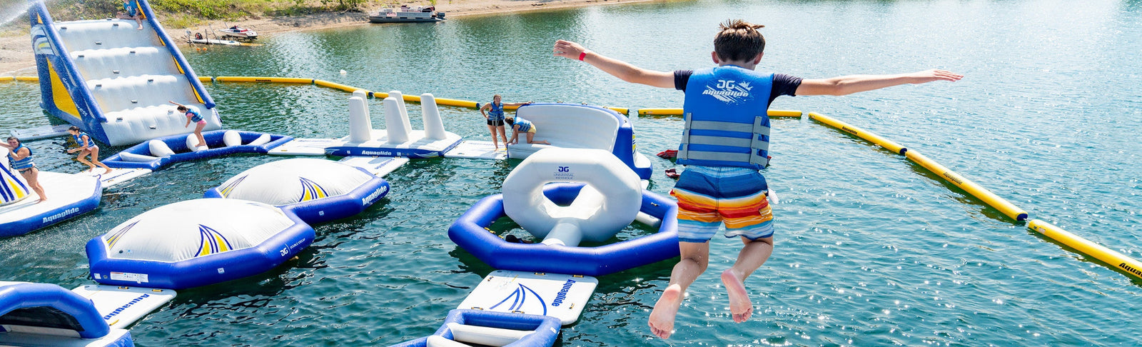 Child jumping into water from inflatable obstacle course.