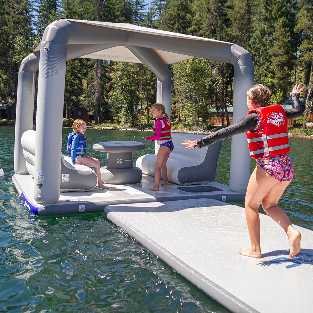 Kids playing on Lakefront Mini Park 2, an Aquaglide inflatable dock with seats, by the lake.