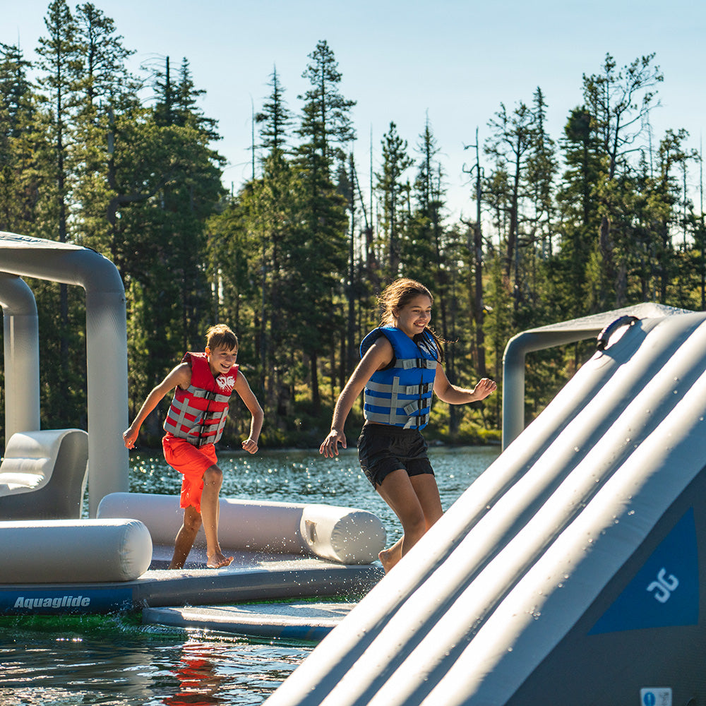 Kids in life vests play on a Lakefront Mini Park 5 by the trees.