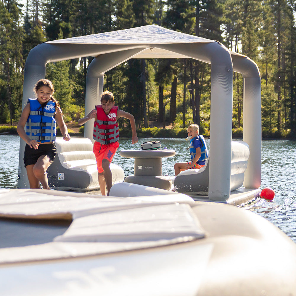 Three kids in life jackets enjoy a Lakefront Mini Park 5 float on the lake.