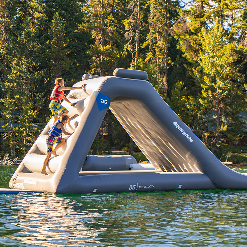 Kids scaling the Velocity Slide 10.0 in an Aquaglide residential park by the lake.