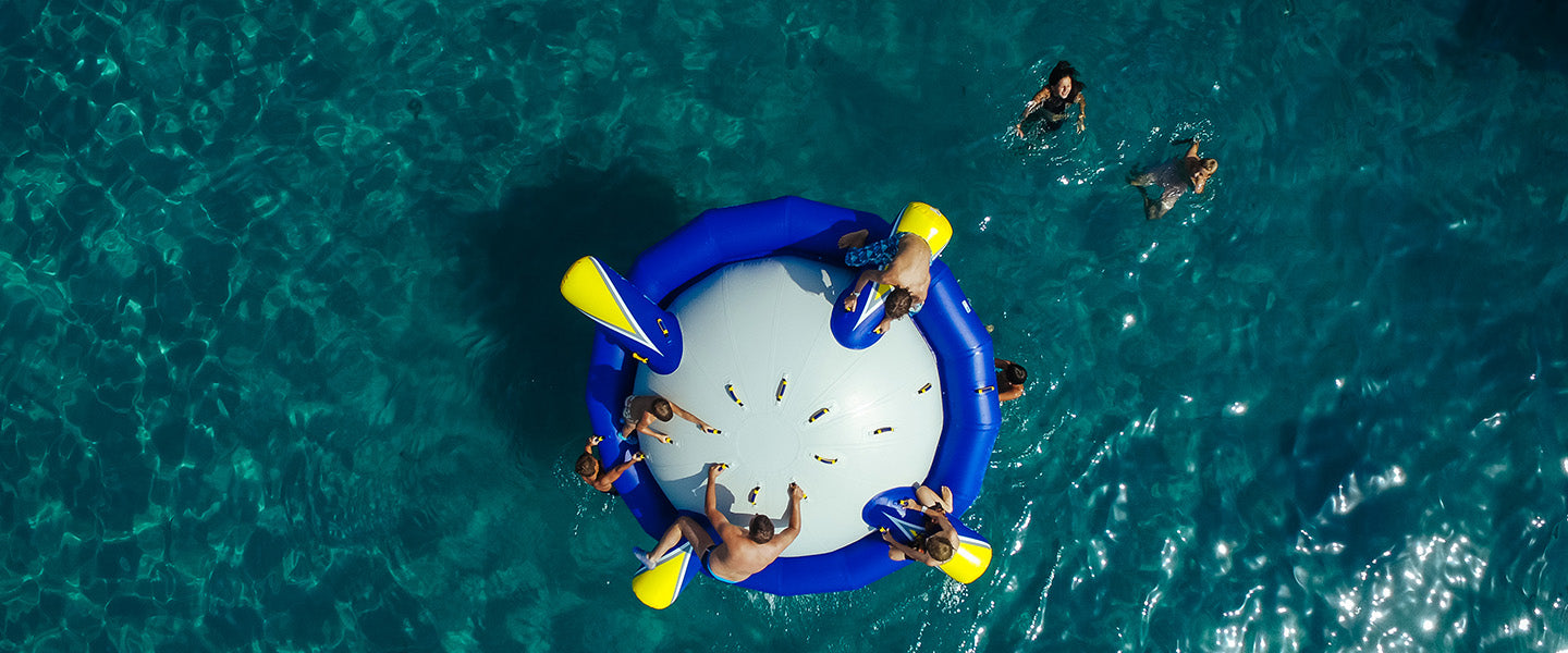 People enjoy a water trampoline in a clear blue sea.