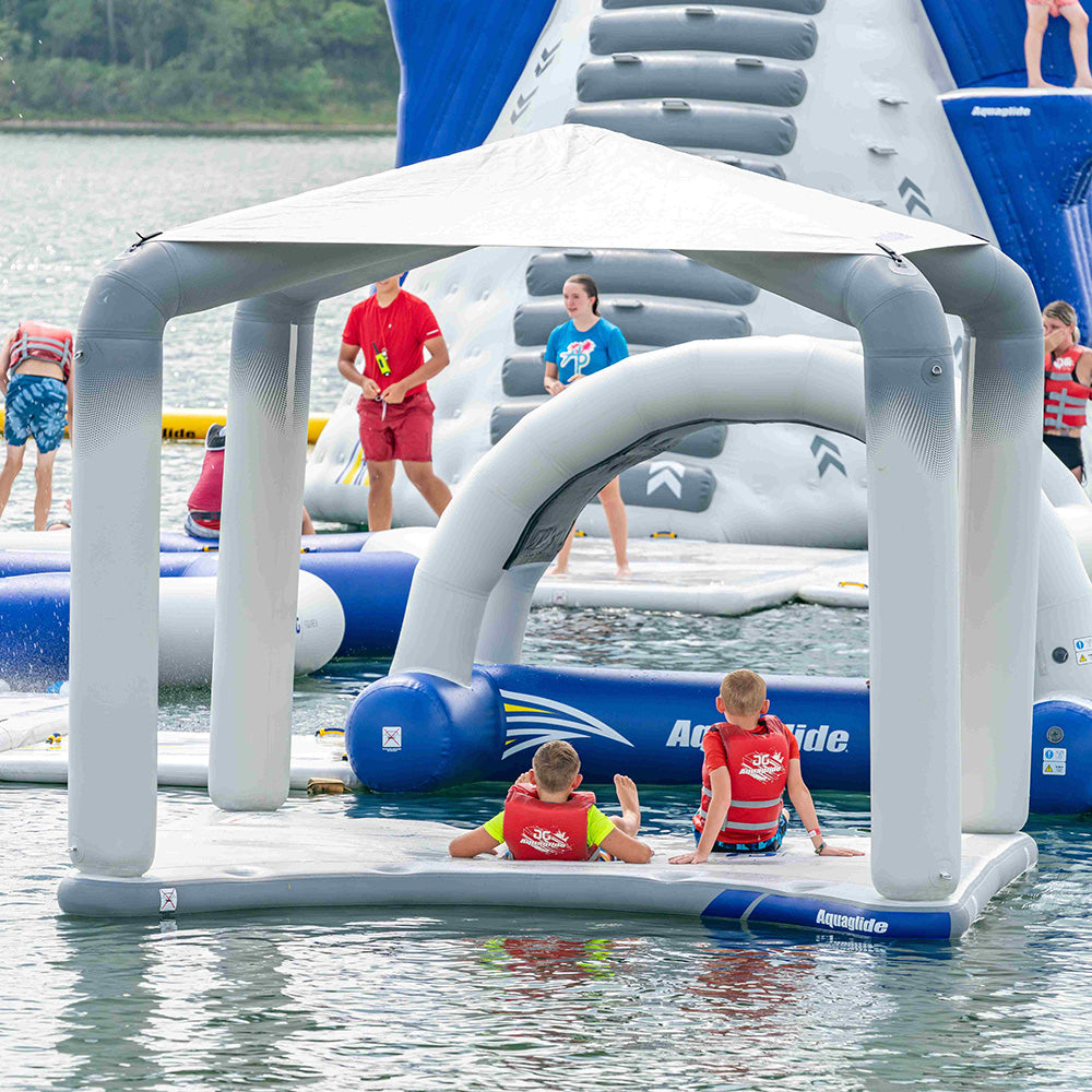 Kids enjoy the inflatable water park, supervised by an adult from a nearby Riviera Lounge.