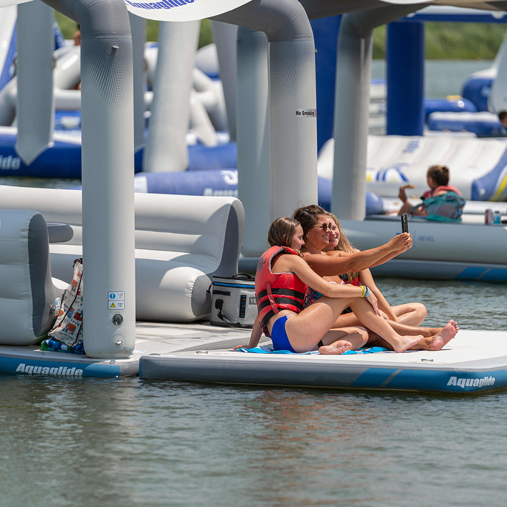 People in swimsuits on an inflatable Solarium, snapping a selfie.