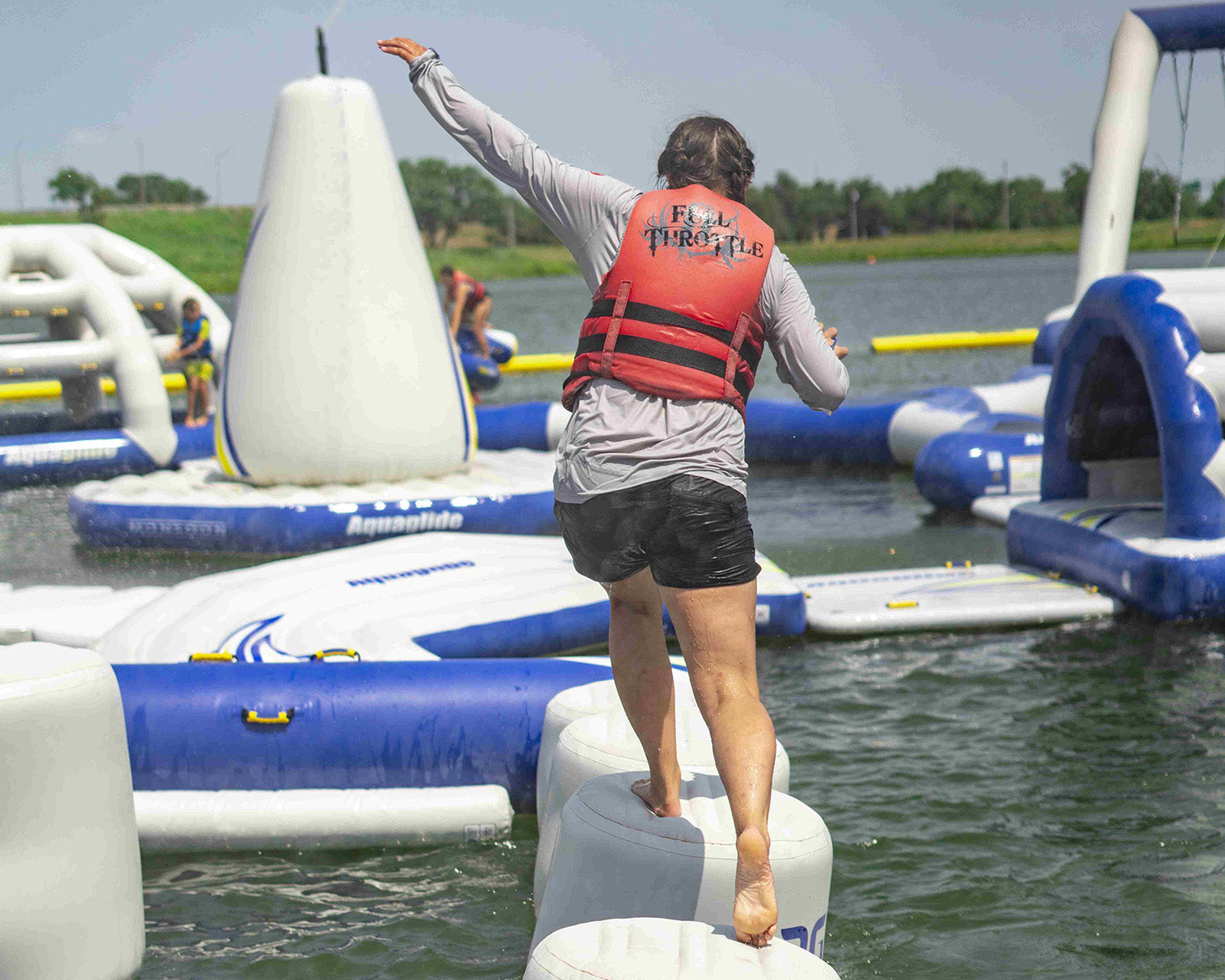 Person balancing on inflatable water course in a life jacket.