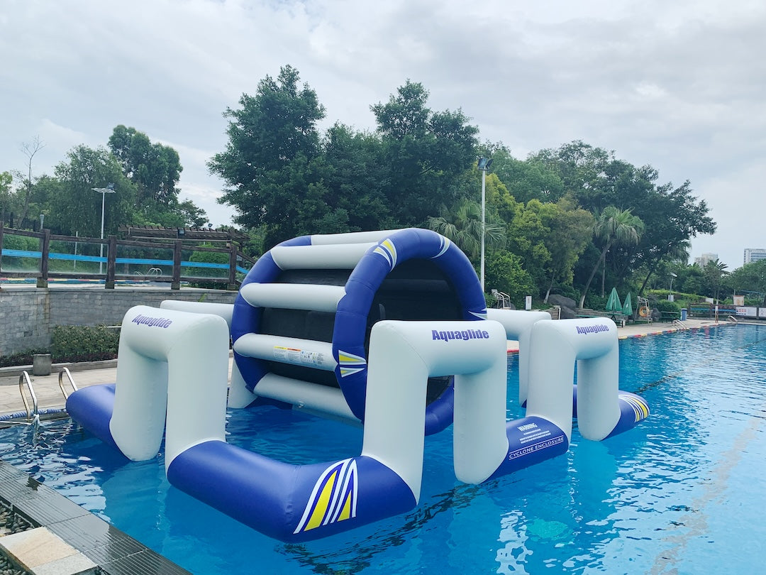 Cyclone Enclosure inflatable with arched entrance and bars, floating in a clear blue pool.
