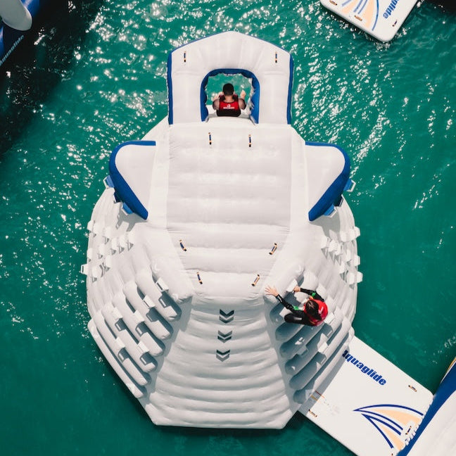 Top view of two people wearing red life jackets one is sliding down while the other is climbing up the climbing steps.