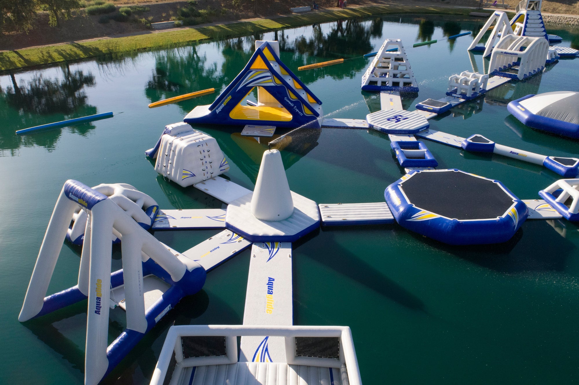 Floating water park with various inflatable obstacles on a calm body of water.