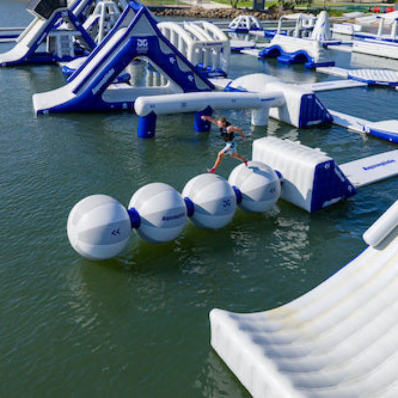 Aerial view of water park with person running across connected Helix inflatables.