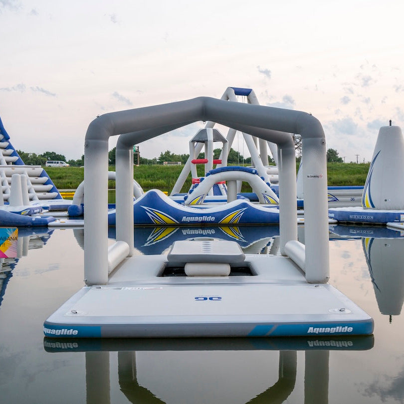 The Solarium inflatable lounge shown with other Aquaglide waterpark features on a calm lake.