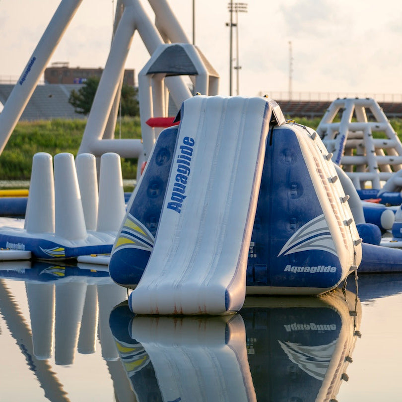 Front view of an inflatable Aquaglide aquapark obstacle course at sunrise showing multiple Aquapark features in the background.
