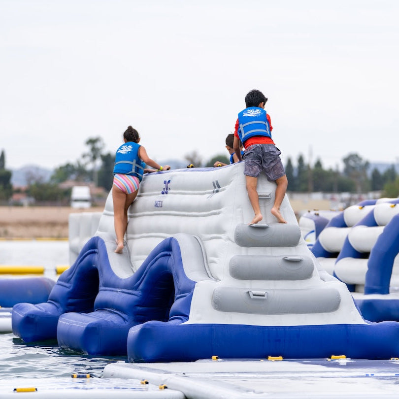 Kids climb up the side of the Arete 20 inflatable using molded handholds and footholds.