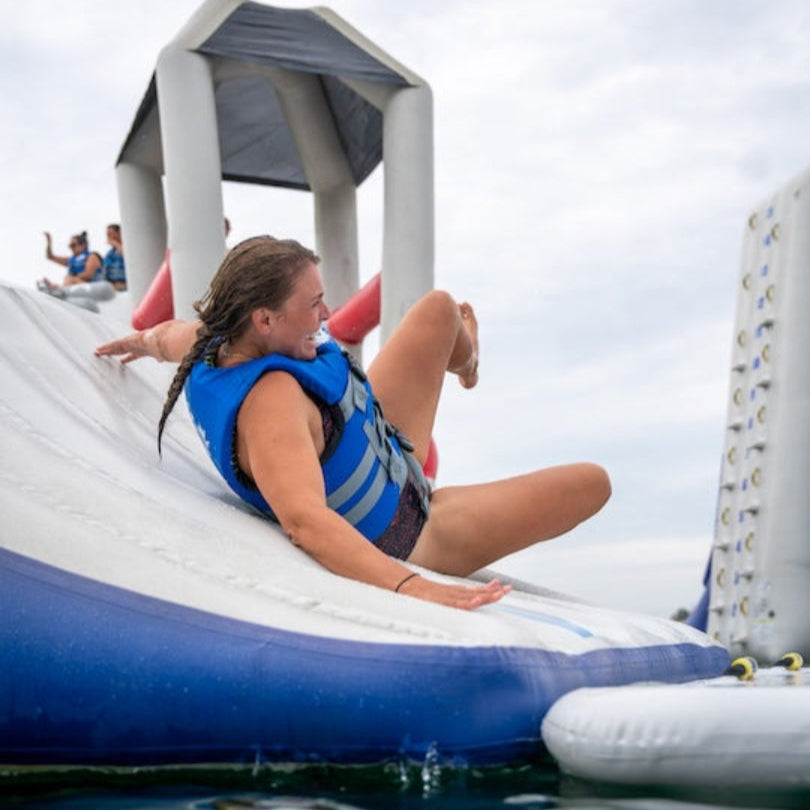 Woman in blue vest sliding down the Parkway 20 inflatable curve.