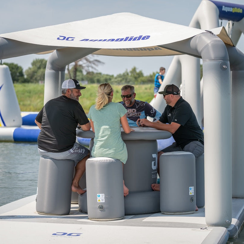 Four people sit on inflatable stools under a canopy on the Solarium inflatable lounge. 