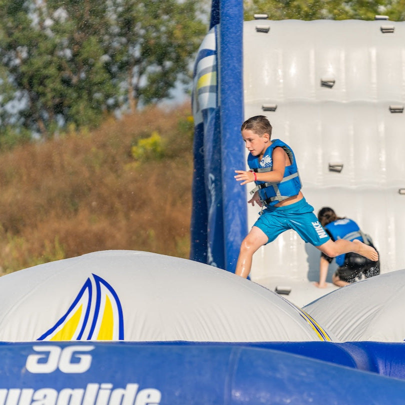 Boy in blue life vest runs across the top of Double Icecap inflatable domes.
