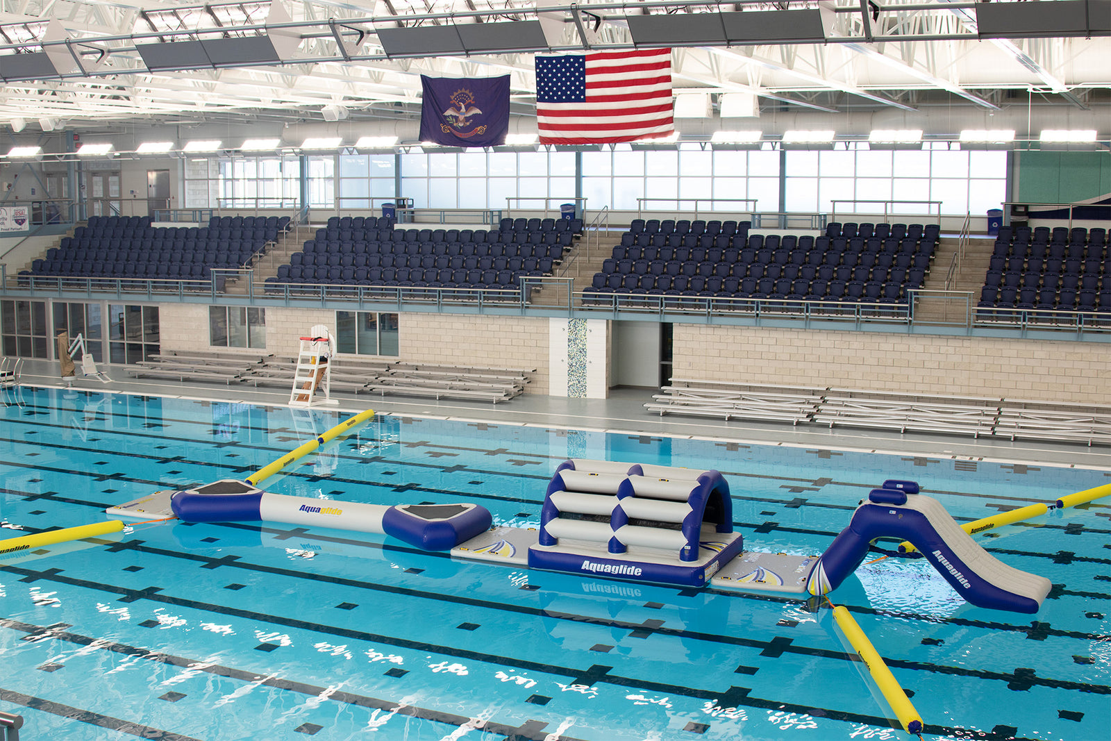 Indoor pool with inflatable obstacle course under American and Pennsylvania flags.