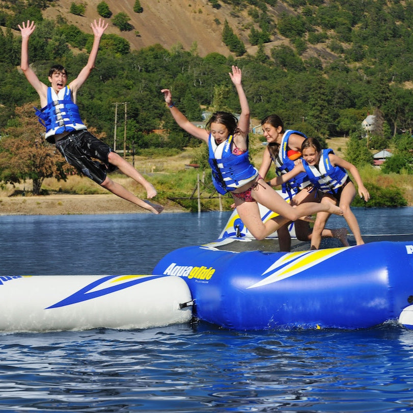 Four kids leap from the Rebound 20 in midair over a lake.